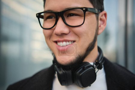 Téléchargez les photos : An Asian guy businessman in a headphones closeup shot, outdoor - en image libre de droit