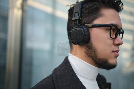Photo for An Asian guy businessman in a headphones closeup shot, outdoor - Royalty Free Image