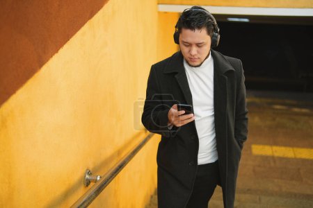 Téléchargez les photos : An Asian guy in a headphones rises from the underpass - en image libre de droit