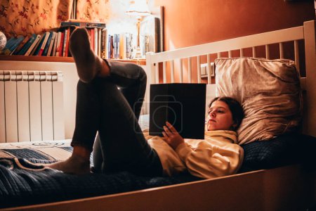 Téléchargez les photos : Woman reading a book lying in bed at night - en image libre de droit