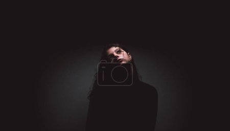 Téléchargez les photos : Fine art photography of woman with curly hair against black background - en image libre de droit