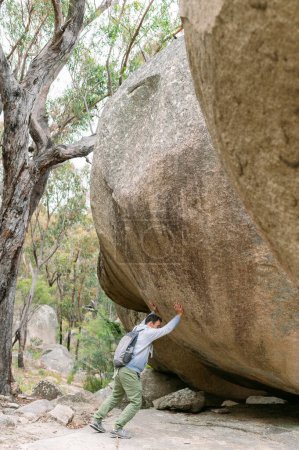 Photo for Hiker man 50 trying to move a heavy granite stone in Girraween N - Royalty Free Image