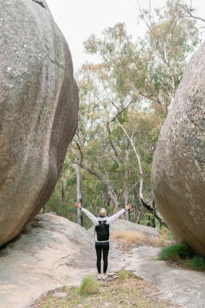 Photo for Hiker woman 40 standing with open arms between granite rocks in - Royalty Free Image