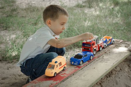 Foto de Pequeño niño está jugando con coches de juguete en el patio al aire libre - Imagen libre de derechos