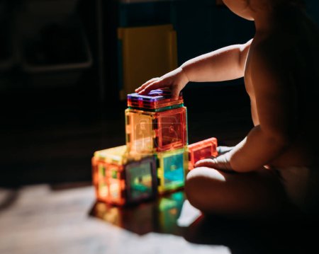 Foto de Bebé jugando bloques de azulejos magnéticos en la luz de la mañana - Imagen libre de derechos