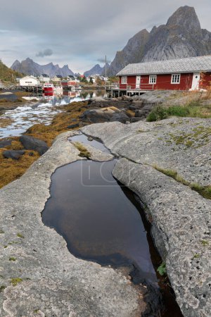 Téléchargez les photos : Red norvegian rorbu houses in fisherman village with mountains in - en image libre de droit
