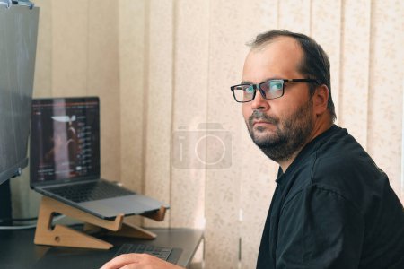 Foto de A European man in glasses works at a computer - Imagen libre de derechos