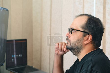 Foto de A European man in glasses works at a computer - Imagen libre de derechos