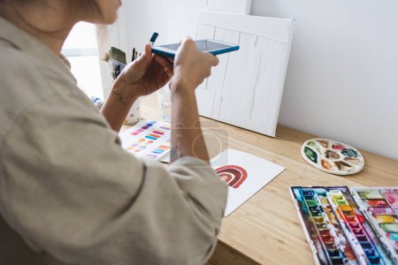 Téléchargez les photos : Person Taking Picture of Painting on Desk with Art Materials - en image libre de droit