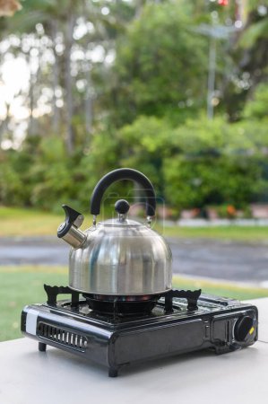 Téléchargez les photos : Vertical shot of Metal kettle teapot on camping gas cooker white - en image libre de droit