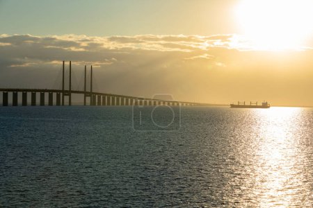 Photo for Cargo Ship and Oresund Bridge during sunset, Malmo, Sweden - Royalty Free Image