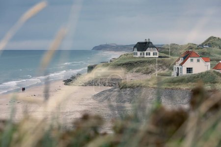Foto de Beach houses with a couple holding hands while walking on the beach - Imagen libre de derechos