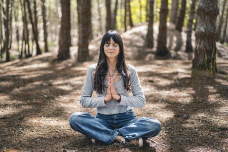 Photo for Front view of a woman clasping hands in the woods. Namaste pose. - Royalty Free Image