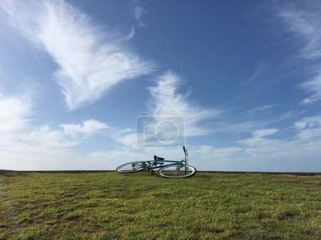 Photo for Blue single speed bike on grass with beautiful summer sky - Royalty Free Image