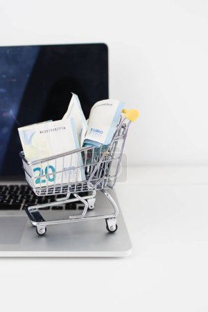 Foto de Ecommerce Shopping Cart Full of Money on a Laptop - Imagen libre de derechos