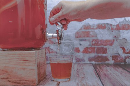 Téléchargez les photos : Woman's hand opening the tap of a bottle of home-made fermented kombucha tea - en image libre de droit