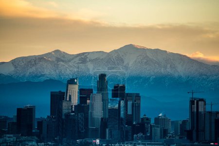 Foto de Los Angeles Skyline Contrasts Snow Capped Mountains - Imagen libre de derechos
