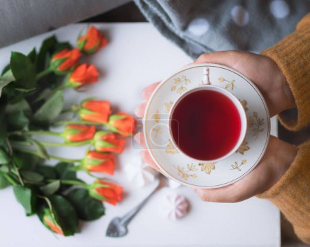 Foto de Tea cup at tea time with orange rose flowers - Imagen libre de derechos