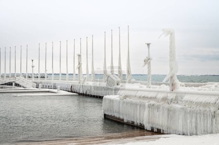 Photo for Ice covered poles on pier on Lake Ontario after a winter storm. - Royalty Free Image