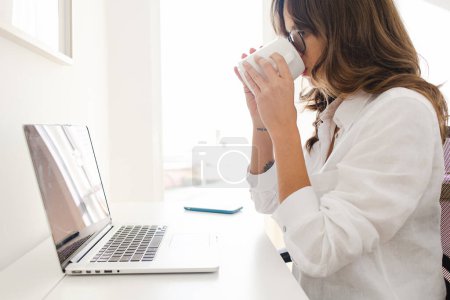 Foto de Woman Working from Home Office Holding a Mug Drinking Coffee - Imagen libre de derechos