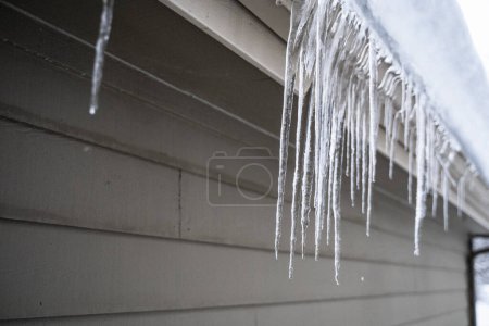 Foto de Melting Icicles Hanging Off House in Winter - Imagen libre de derechos