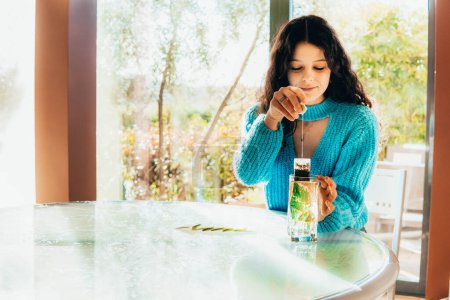 Téléchargez les photos : Single woman preparing a tea in the kitchen against bamboo - en image libre de droit