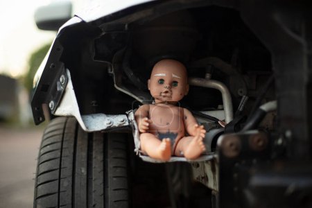 Foto de Baby doll on car wheel. Tuning Machine. Doll inside machine mechanism. Baby sits in transport. - Imagen libre de derechos