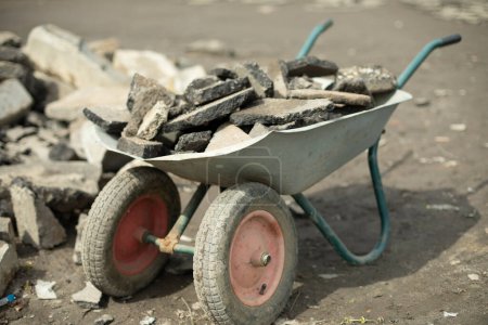 Téléchargez les photos : Garden cart with asphalt. Broken asphalt inside cart. - en image libre de droit