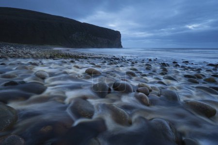 Photo for River flows over rounded sandstone rocks at Rackwick bay, Hoy, Orkney, Scotland - Royalty Free Image