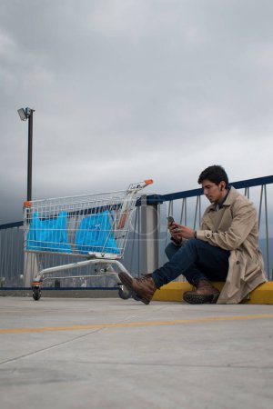 Téléchargez les photos : Market car and man looking his phone in a parking on cloudy day - en image libre de droit