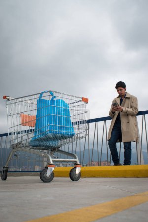 Téléchargez les photos : Voiture de marché et homme regardant son téléphone dans un parking par temps nuageux - en image libre de droit