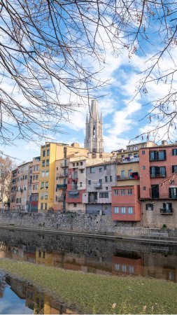 Foto de Girona, Spain : january 2023 : Colorful houses reflected in the Onyar river, in Girona, Catalonia, Spain. Church of Sant Feliu and Cathedral of Santa Mara in the background in 2023. - Imagen libre de derechos