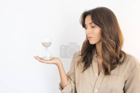 Téléchargez les photos : Young Woman Looking at an Hourglass - en image libre de droit