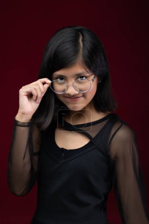 Téléchargez les photos : 12 year old girl portrait isolated on red background wearing gla - en image libre de droit