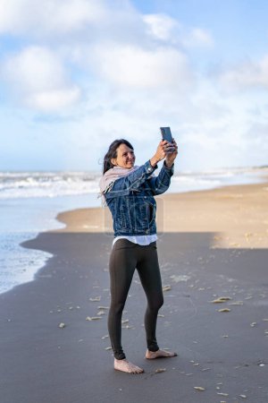 Téléchargez les photos : Portrait of a woman taking selfies on the beach - en image libre de droit