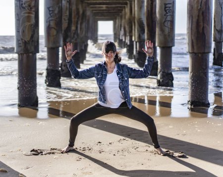 Téléchargez les photos : A woman practicing yoga outdoors, doing Goddess with Cactus Arms (Utkata Konasana) pose. - en image libre de droit