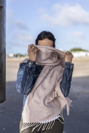 Photo for Portrait of a shy woman covering her face with a scarf - Royalty Free Image