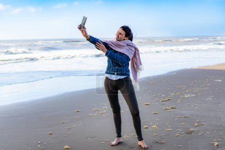 Photo for Portrait of a woman taking selfies on the beach - Royalty Free Image