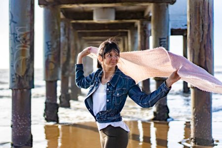 Téléchargez les photos : Woman under a pier holding a scarf on the wind - en image libre de droit