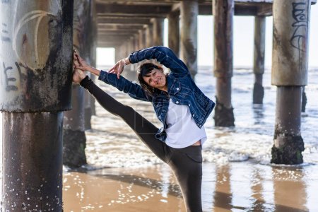 Téléchargez les photos : A smiling woman doing stretching exercises outdoors while looking at camera - en image libre de droit