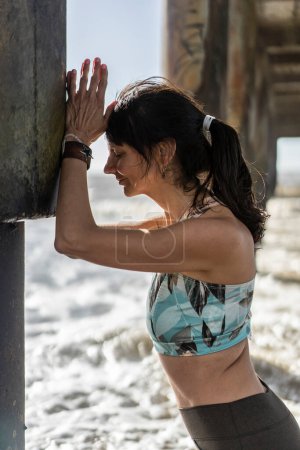 Foto de Portrait of a woman inhaling and exhaling under a pier at the beach - Imagen libre de derechos