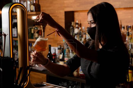 Photo for Young girl serving a glass of beer in a bar. waitress concept - Royalty Free Image