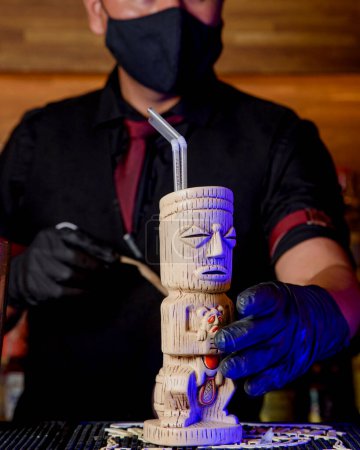 Foto de Bartender with mask preparing cocktail at a bar counter - Imagen libre de derechos