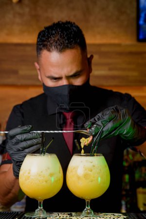 Téléchargez les photos : Black man bartender with mask preparing a cocktail. drinks concept - en image libre de droit
