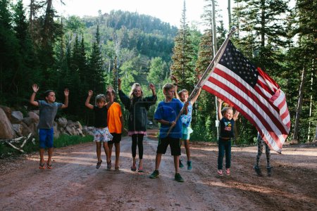 Foto de Niños saltan con emoción con bandera americana el 4 de julio - Imagen libre de derechos
