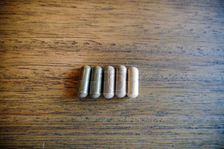 Foto de Medication Capsules Lined Up On Wood Table - Imagen libre de derechos