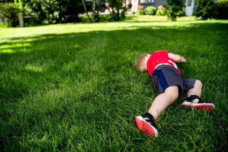 Téléchargez les photos : Jeune garçon roulant dans l'herbe en été - en image libre de droit