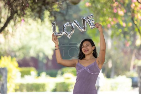 Photo for Mexican brunette holding love balloon letters, woman's day, self love - Royalty Free Image