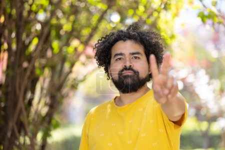 Photo for Portrait of a Mexican man with afro and beard making peace sign - Royalty Free Image