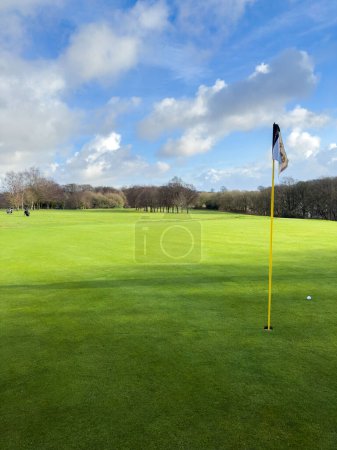 Téléchargez les photos : Flag and the hole at golf club blue sky summers day with some cl - en image libre de droit